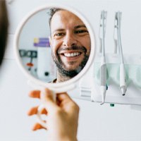 Bearded dental patient checking smile in mirror