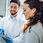 A dentist showing a female patient her dental X-rays and discussing her eligible for dental implants