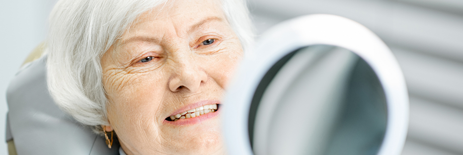 Senior dental patient admiring her new smile with All-on-X dental implants in Bellingham