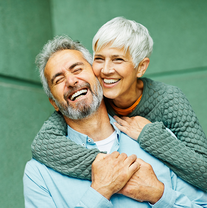 Senior couple hugging against a green background