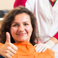 Woman in dental chair giving thumbs up