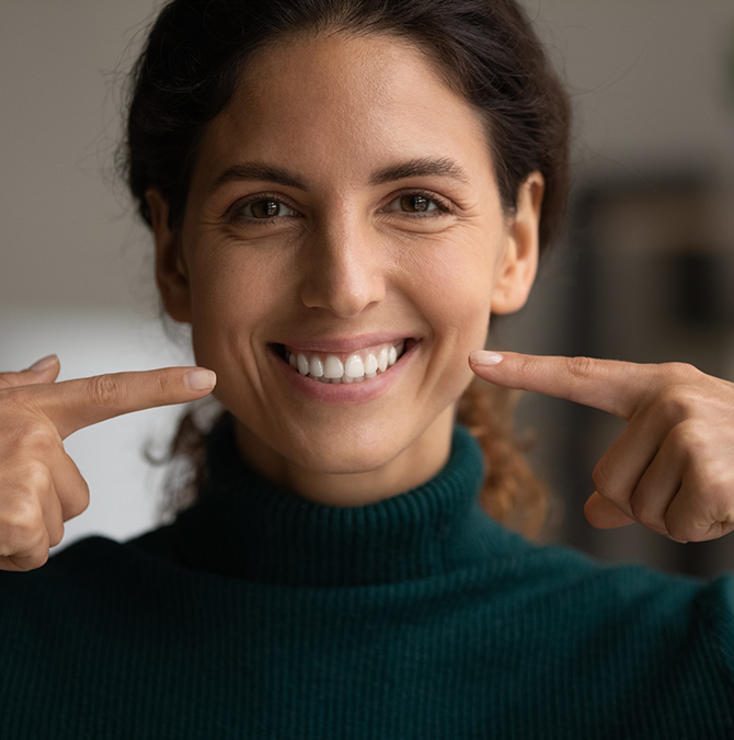 Young woman pointing to her smile
