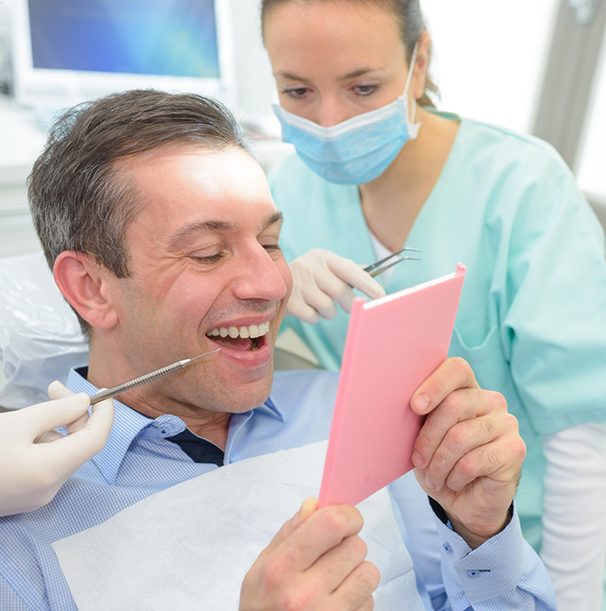 Dental patient admiring his new smile in a mirror