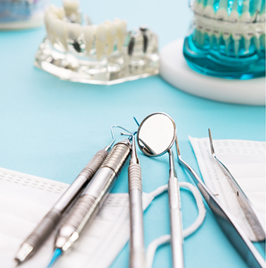 Dental instruments laying next to a face mask and models of teeth