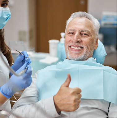 Smiling senior man giving a thumbs up in the dental chair