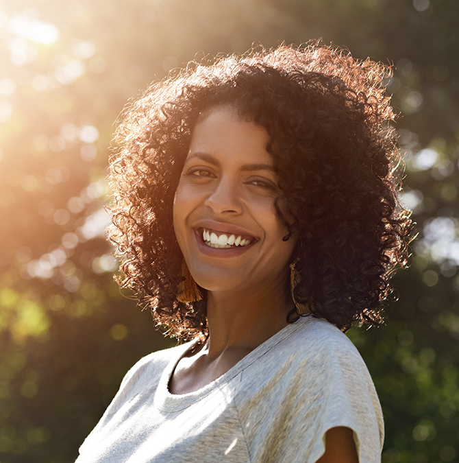 Woman in a light gray blouse smiling outdoors