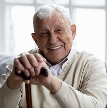 Senior man sitting and leaning on his cane