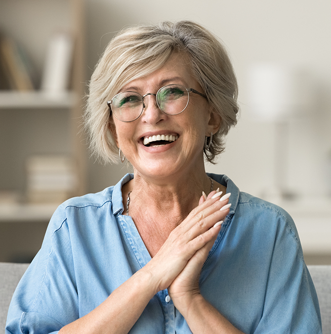 Smiling woman in a light blue blouse clasping her hands together