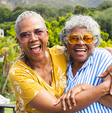 Two senior women laughing together outdoors