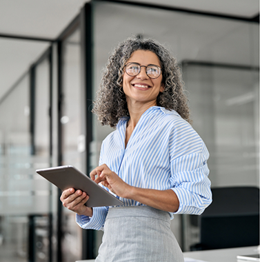 Smiling older woman holding a tablet in an office
