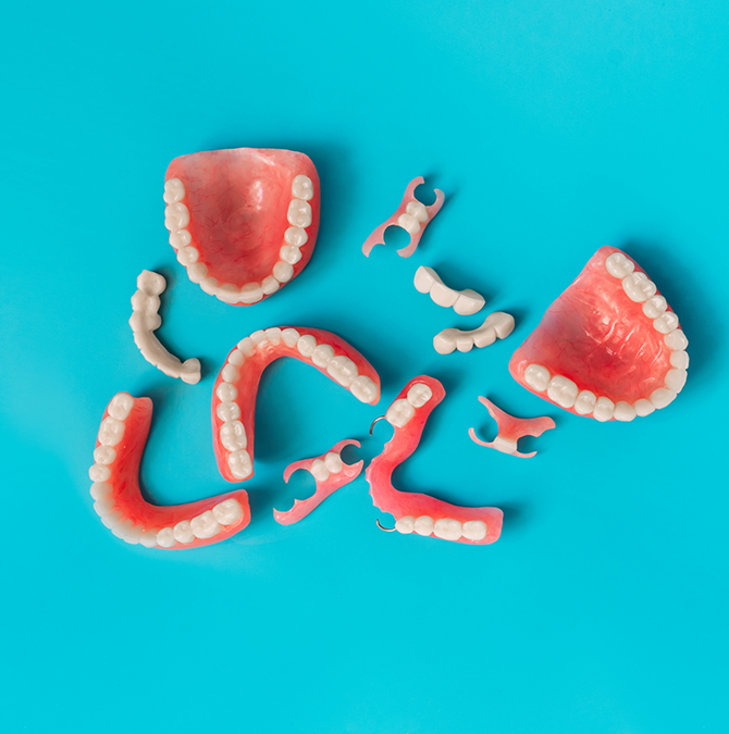 Several types of dentures laying on a light blue surface