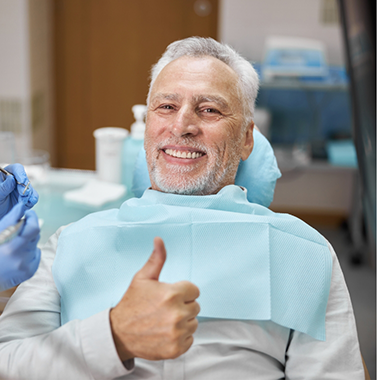Senior man in the dental chair giving a thumbs up