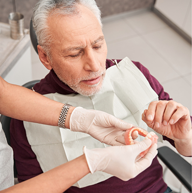 Dentist handing a senior patient his new dentures