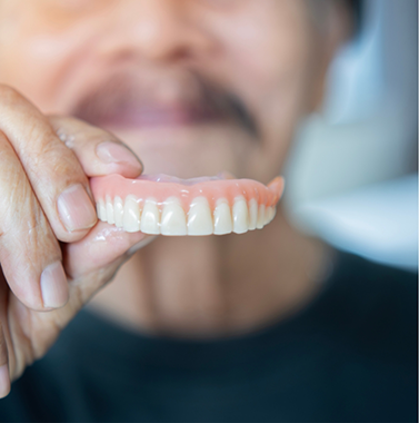 Man holding a full upper denture