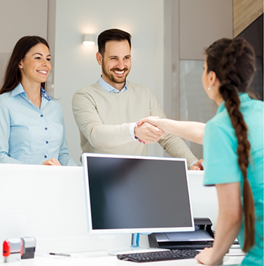 Man shaking hands with a dental team member at the front desk