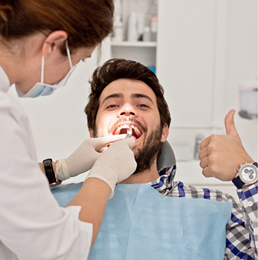 Man giving a thumbs up while getting a dental treatment