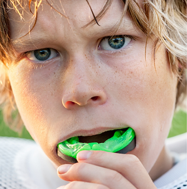 Boy placing a mouthguard over his teeth