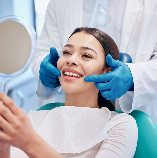 Young woman in the dental chair looking at her smile in a mirror