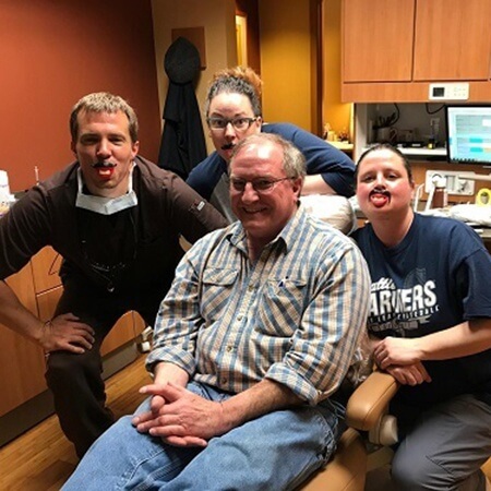 Patient in dental chair and team members smiling