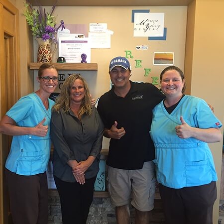 Team members and patient giving thumbs up