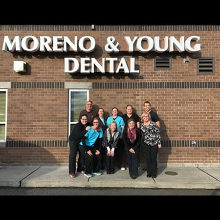 Moreno & Young Dental team posing beneath outdoor sign