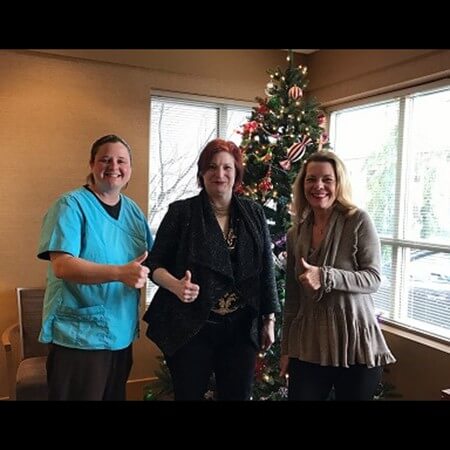 Team members posing with Christmas tree