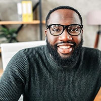 a smiling person sitting at a desk