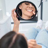 Dental patient admiring her smile in mirror