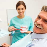 senior man asking his dentist questions about implant dentures 