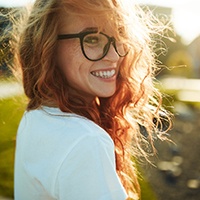 Red-haired woman with glasses outside smiling