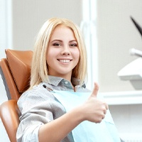 Woman with thumb up smiling after getting dental implants in Bellingham