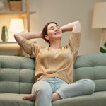 Woman in tan top relaxing while sitting on couch