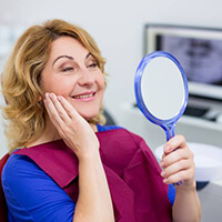 woman admiring her smile in a small hand mirror