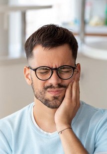 a man holding his cheek due to tooth pain