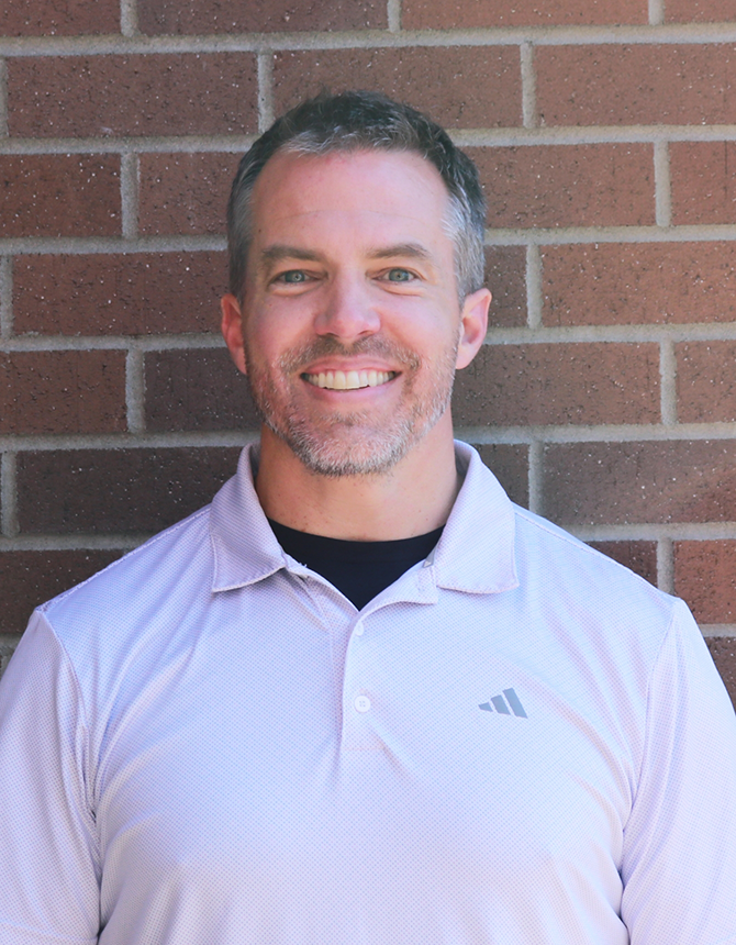 Doctor Young smiling with a red brick wall in the background