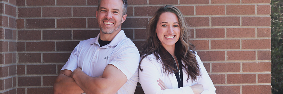 The two dentists at Young Dental smiling and standing back to back