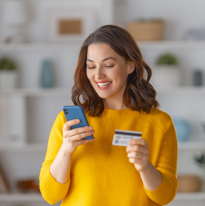 Woman holding her phone and her bank card