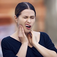 Woman grimacing and holding cheek