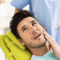 Man in dental chair holding jaw