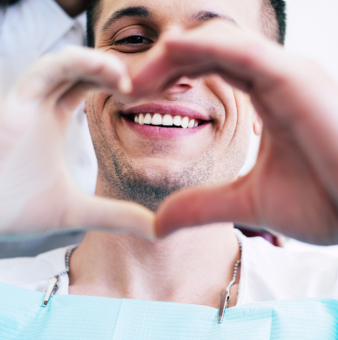 Smiling man making a heart shape with his fingers