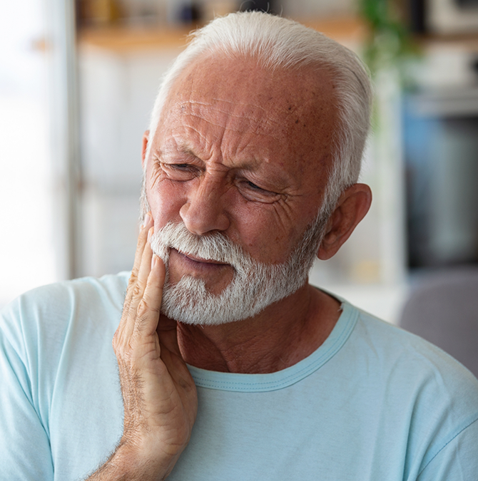 Senior man holding his cheek in pain