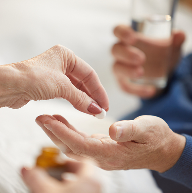 Person handing a pill to someone else