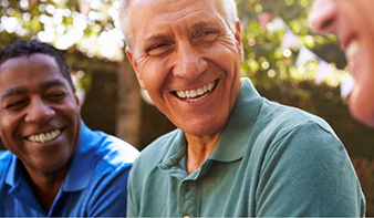 Three older men laughing outdoors