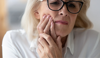 Older woman holding her cheek in pain