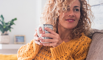 Woman sitting on a couch and holding a mug of coffee