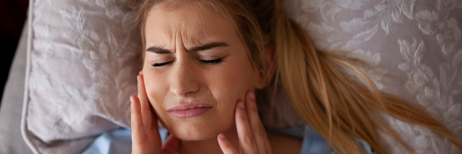 Woman holding both sides of her jaw in pain