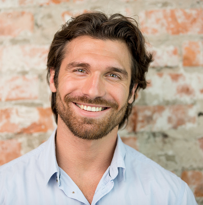 Smiling man in a pale blue collared shirt