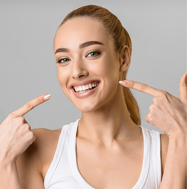 Blonde woman pointing to her smile