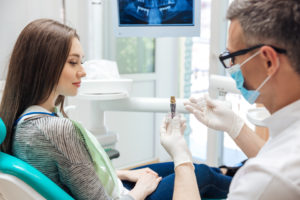 Dentist showing patient dental implant model