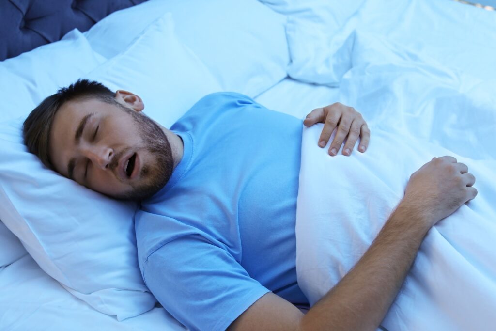 Man lying in bed with mouth open like he's snoring